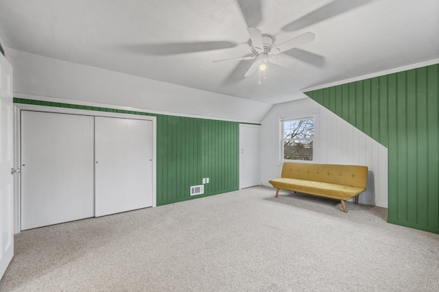 living area with lofted ceiling, ceiling fan, and carpet flooring