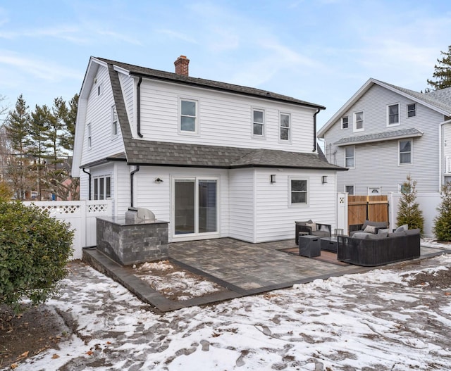 snow covered house with area for grilling, an outdoor hangout area, and a patio