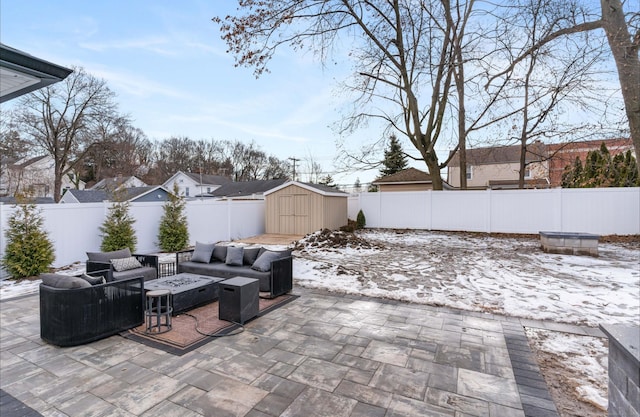 snow covered patio featuring a storage unit and an outdoor living space with a fire pit