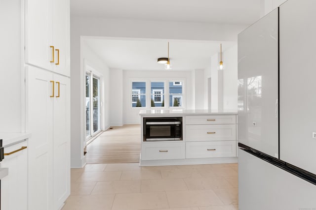 kitchen featuring decorative light fixtures, built in microwave, white cabinets, white fridge, and light tile patterned floors