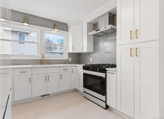 kitchen featuring white cabinetry, sink, range with gas stovetop, and wall chimney exhaust hood