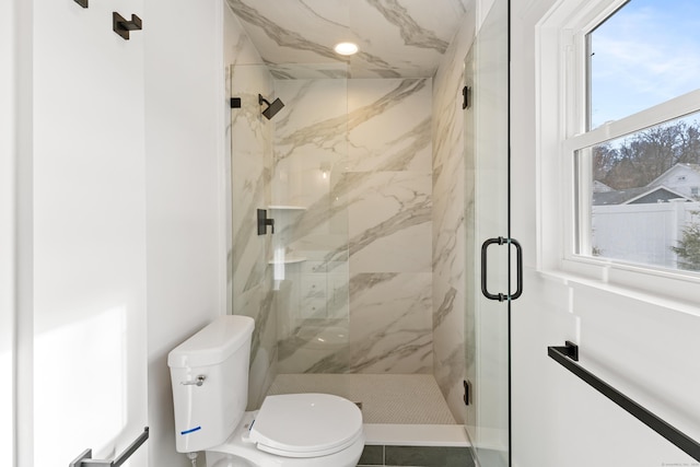 bathroom featuring a shower with door and toilet