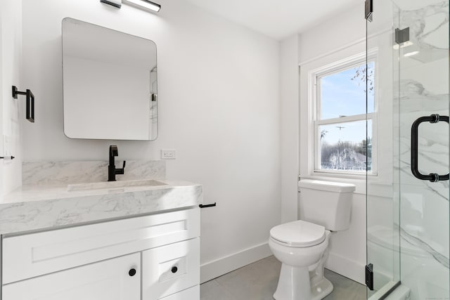 bathroom featuring vanity, a shower with shower door, and toilet