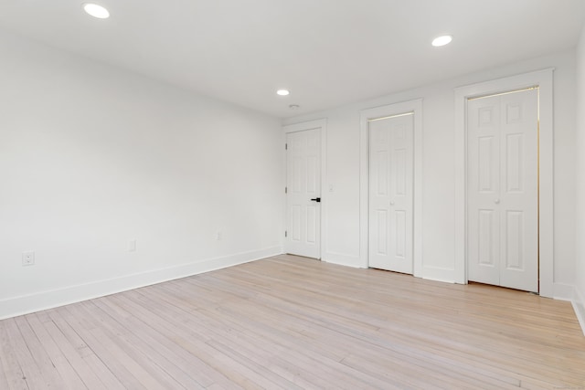 unfurnished bedroom with multiple closets and light wood-type flooring