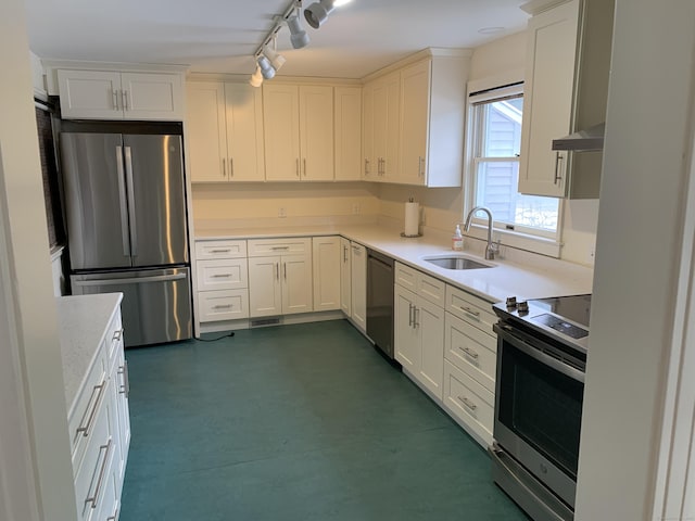 kitchen featuring appliances with stainless steel finishes, sink, wall chimney range hood, and white cabinets