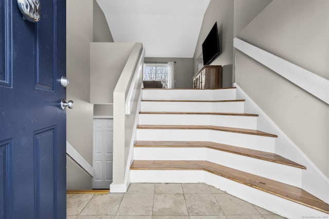 staircase featuring lofted ceiling and tile patterned flooring