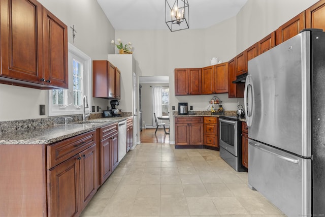 kitchen featuring sink, hanging light fixtures, light tile patterned floors, dark stone countertops, and appliances with stainless steel finishes