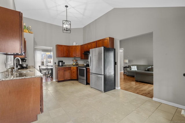 kitchen with pendant lighting, sink, stone counters, appliances with stainless steel finishes, and high vaulted ceiling