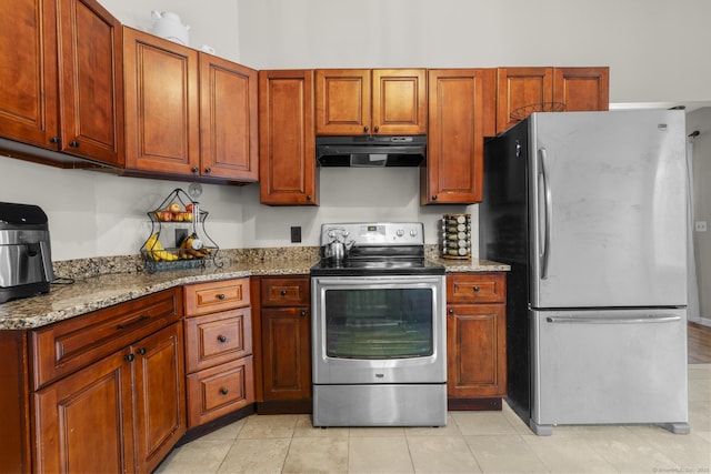 kitchen featuring light stone counters, stainless steel appliances, light tile patterned floors, and exhaust hood