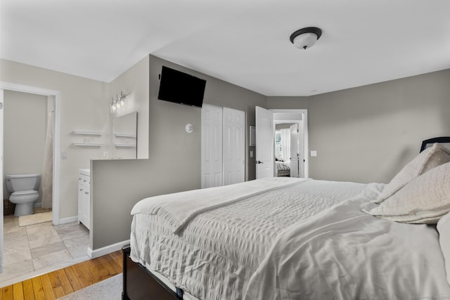 bedroom with connected bathroom, light hardwood / wood-style floors, and a closet