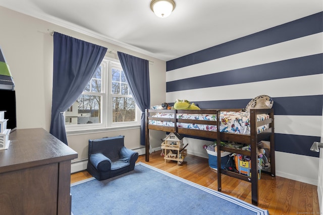 bedroom with hardwood / wood-style flooring and a baseboard heating unit