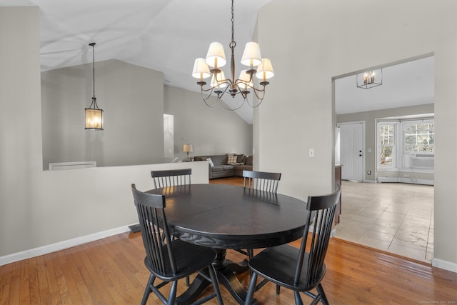 dining room with cooling unit, a notable chandelier, high vaulted ceiling, and light wood-type flooring