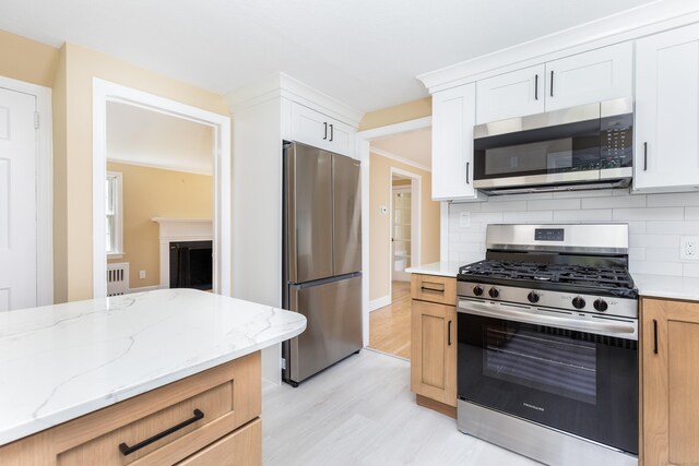 57 Saint James St, West Hartford, CT 06119 - kitchen with appliances with stainless steel finishes, light wood finished floors, decorative backsplash, light stone countertops, and white cabinets