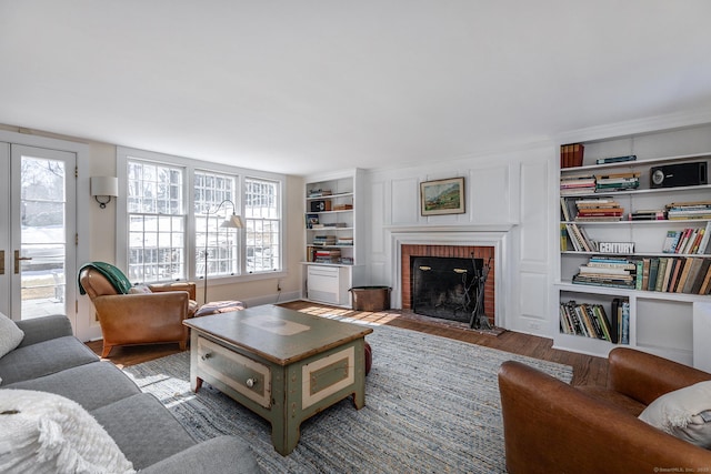 living area featuring built in shelves, a fireplace, and wood finished floors