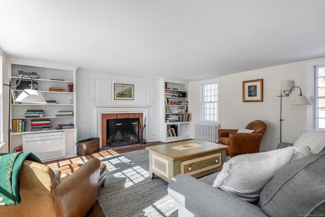 living room with a healthy amount of sunlight, a brick fireplace, radiator heating unit, and built in shelves