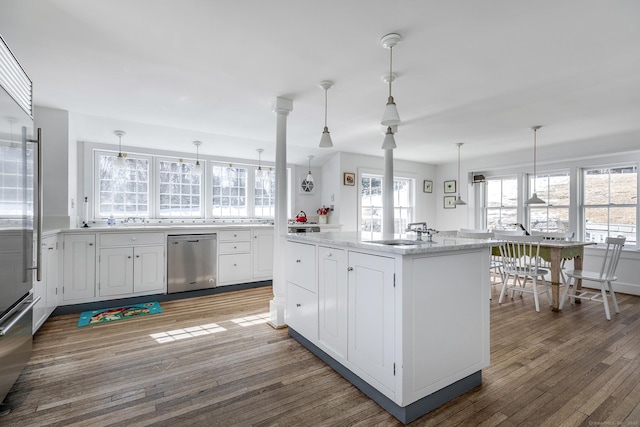 kitchen featuring stainless steel appliances, hanging light fixtures, white cabinetry, a sink, and hardwood / wood-style floors