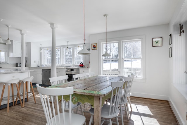 dining space with ornate columns, baseboards, and wood finished floors