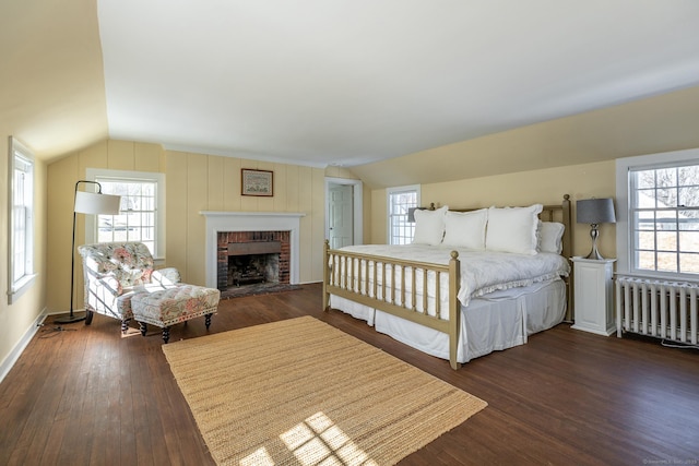 bedroom featuring lofted ceiling, multiple windows, radiator heating unit, and hardwood / wood-style flooring