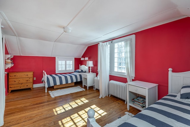 bedroom featuring radiator heating unit, vaulted ceiling, and hardwood / wood-style floors