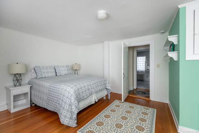 bedroom with baseboards, hardwood / wood-style floors, and radiator