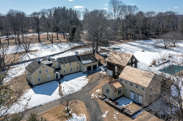 snowy aerial view featuring a wooded view