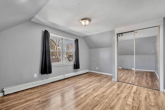 additional living space featuring vaulted ceiling, baseboard heating, and light hardwood / wood-style floors