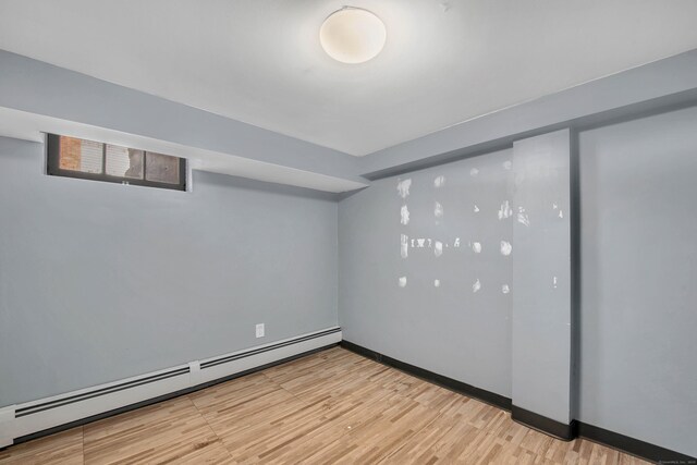 basement with light hardwood / wood-style flooring and a baseboard radiator