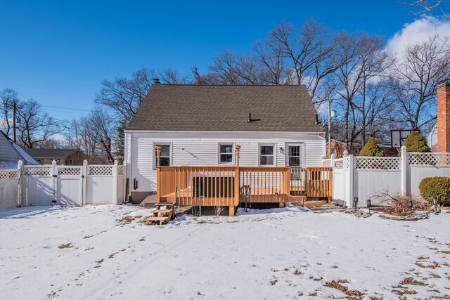 snow covered back of property with a wooden deck