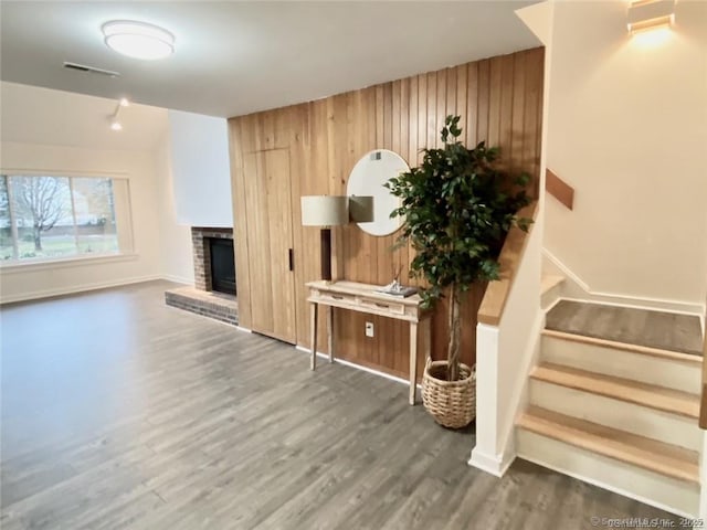 living room featuring a brick fireplace, wooden walls, and dark hardwood / wood-style floors