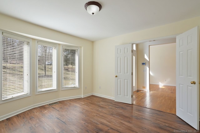 unfurnished room featuring visible vents, baseboards, and wood finished floors