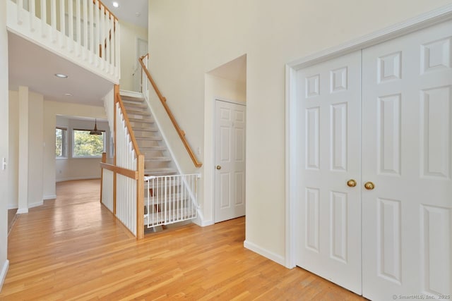 stairway featuring wood finished floors, baseboards, and a towering ceiling