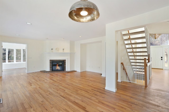 unfurnished living room with recessed lighting, baseboards, light wood-style floors, and a fireplace