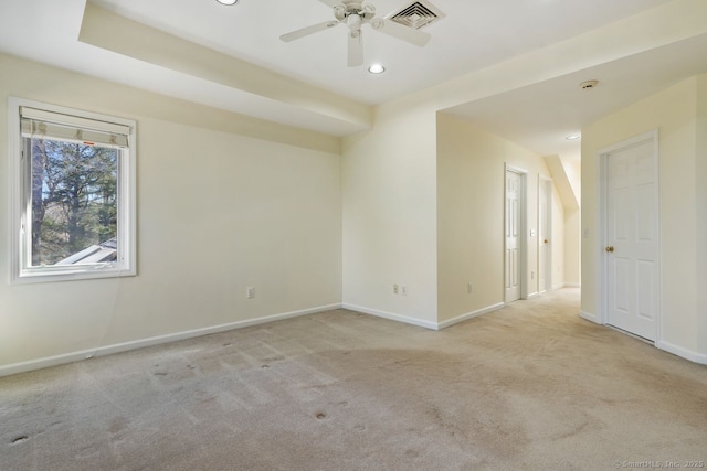 spare room featuring visible vents, light carpet, baseboards, and a ceiling fan