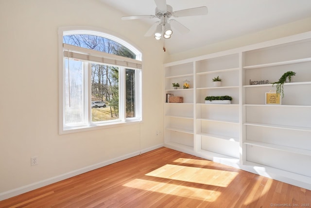 spare room with baseboards, wood finished floors, and a ceiling fan