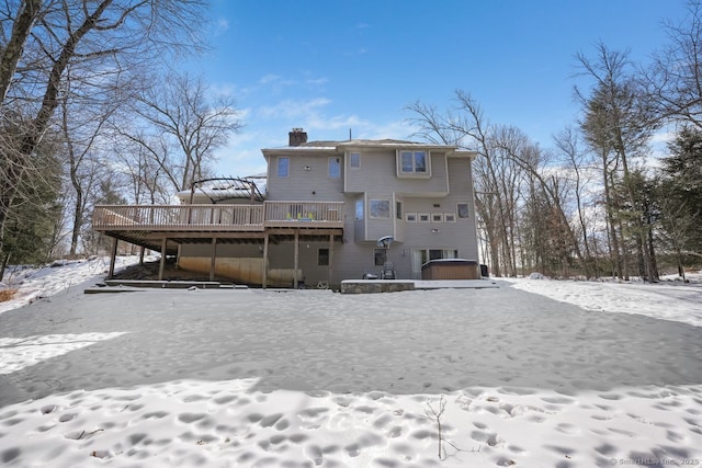 snow covered back of property with a chimney and a deck