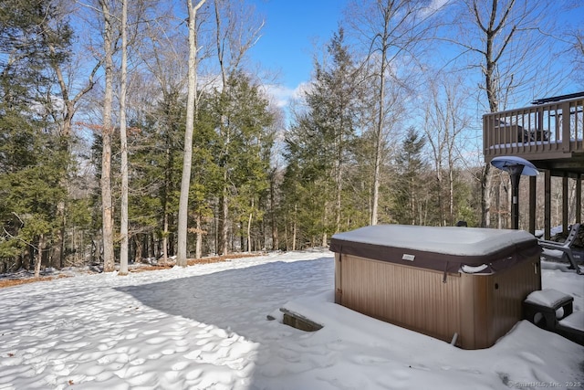 yard covered in snow featuring a wooded view and a hot tub