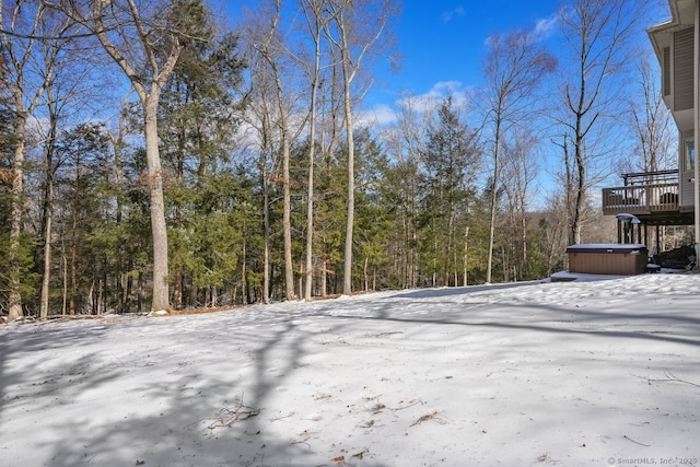 snowy yard with a wooded view and a hot tub