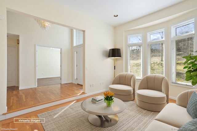 living area featuring plenty of natural light, wood finished floors, and a chandelier