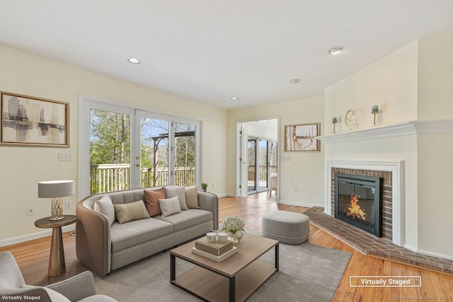 living area with recessed lighting, light wood-type flooring, baseboards, and a fireplace