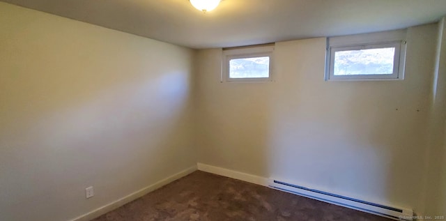 empty room featuring baseboard heating and dark colored carpet