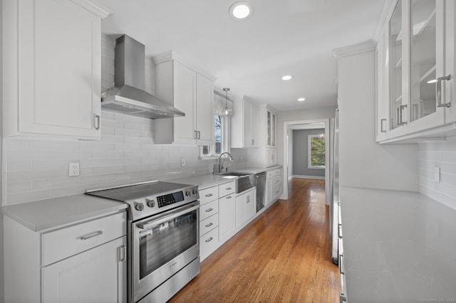 kitchen featuring dishwasher, sink, white cabinets, electric range, and wall chimney range hood