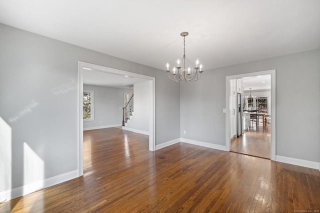 unfurnished dining area with an inviting chandelier and dark hardwood / wood-style flooring