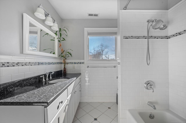 bathroom with tile patterned floors, tiled shower / bath combo, tile walls, and vanity