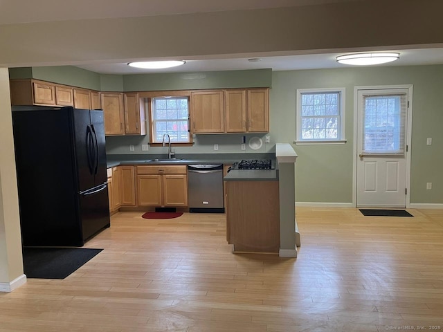 kitchen featuring black refrigerator, dishwasher, sink, range, and light hardwood / wood-style flooring