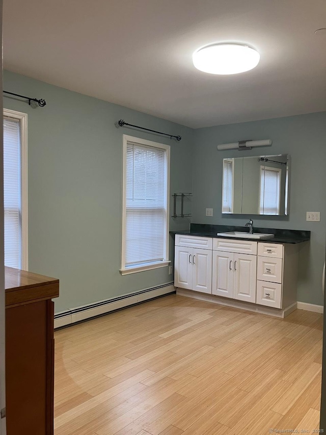 bathroom featuring vanity, hardwood / wood-style floors, and a baseboard heating unit