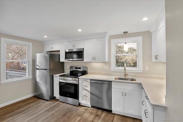 kitchen featuring white cabinetry, appliances with stainless steel finishes, sink, and hanging light fixtures