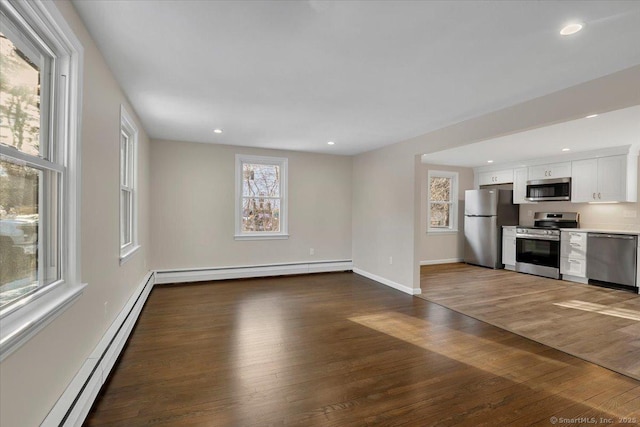 unfurnished living room featuring dark hardwood / wood-style flooring and a baseboard heating unit