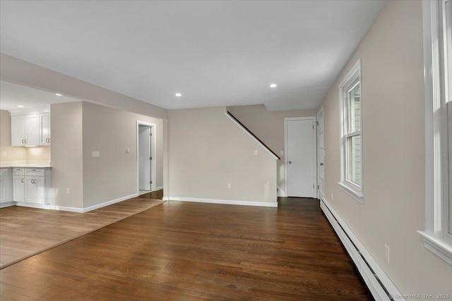 unfurnished living room featuring baseboard heating and hardwood / wood-style floors