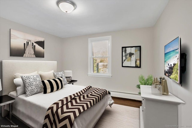 bedroom with a baseboard heating unit and hardwood / wood-style floors