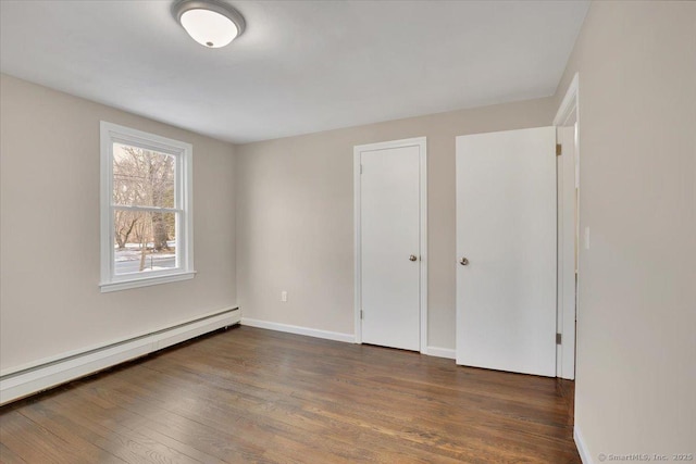 unfurnished bedroom featuring a baseboard radiator and dark hardwood / wood-style floors